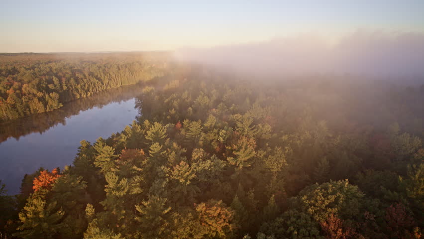 Aerial drone sweep over a river within an autumn landscape.