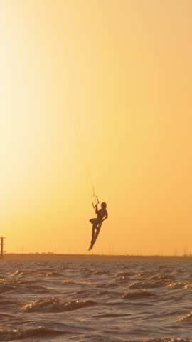 silhouette of skilled kitesurfer complex maneuvers orange sunset silhouette slow motion professional extreme water sports