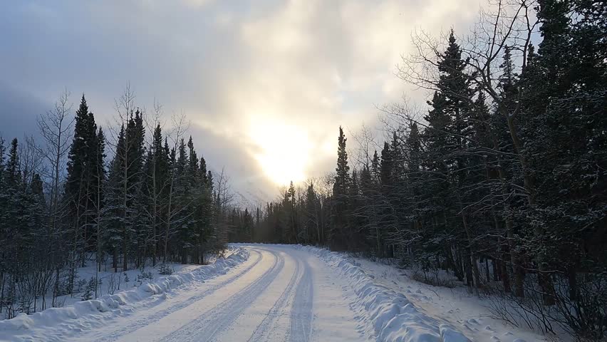 Vehicle point-of-view shot drives along a snow-covered road towards the majestic King