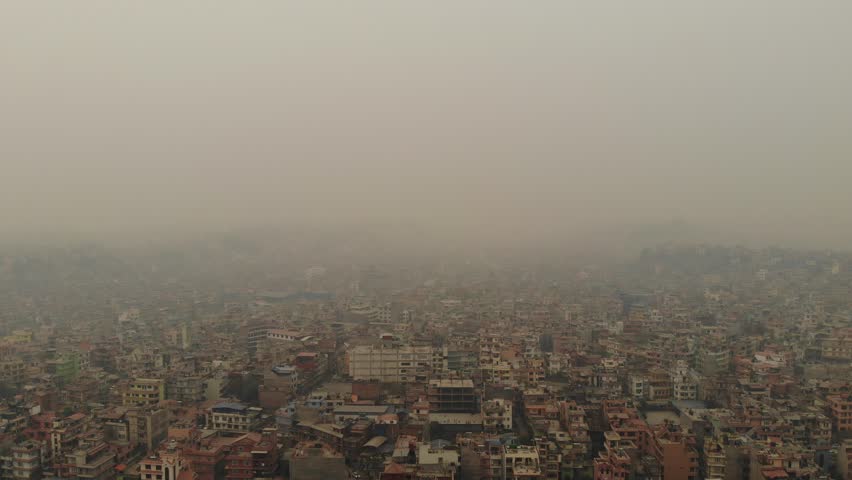 A drone view of Kathmandu shows heavy air pollution spreading across the valley, reducing visibility and creating a dense smog layer over buildings, roads, and surrounding hills.