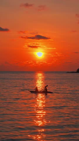 Experience the breathtaking sunset glow over a serene beach in Koh Munnork Thailand. Enjoy the beautiful silhouettes of people walking along the shore by gently lapping waves.