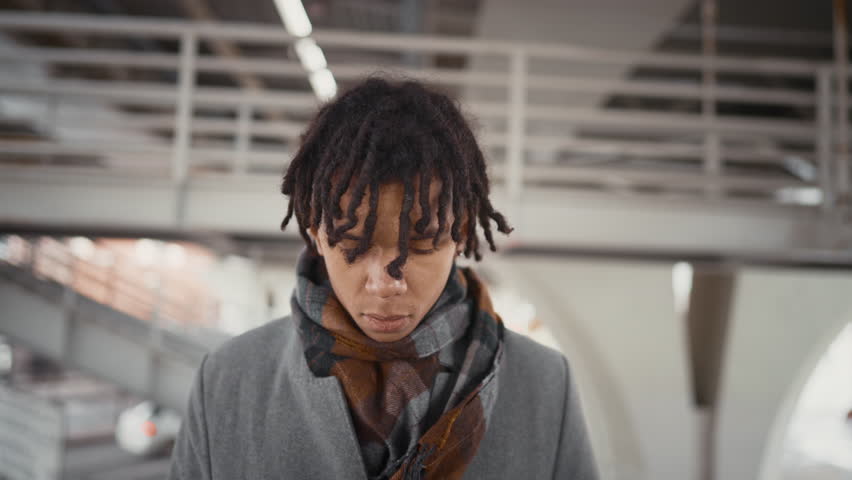 Self-confident young black man looking at camera, portrait in urban landscape. Stay yourself and be unique, diversity of people appearance, african american ethnicity, male passerby on city street