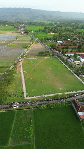 Aerial View Of A Large Park During Festival With Colorful Banner Lines And Village In Background