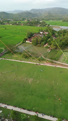Aerial View Of A Large Park During Festival With Colorful Banner Lines And Village In Background