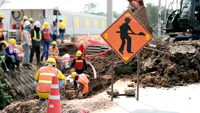 Road Construction Site With Workers And Warning Sign