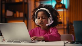 Little girl wearing headset playing video game on laptop, chatting with friends - Powered by Shutterstock - Get 15% off with code: PIKWIZARD15