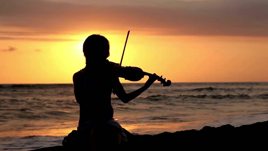 Silhouette Of Violinist Playing Music At Beach Sunset