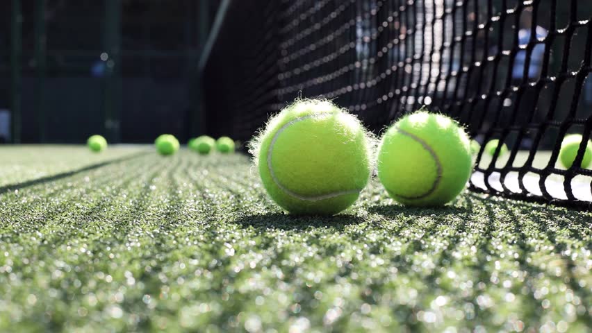 Padel balls on court during sunny day, clean and minimalistic image for sports websites, blogs, and promotional materials.