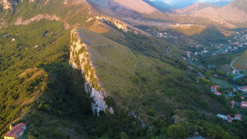 Explore a Mountain Landscape With Green Hills and Small Houses in Italy During Sunset