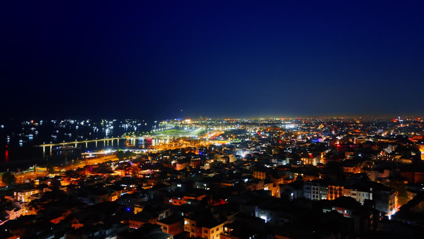 Rising over the luminous panorama of Istanbul, Turkey. Boats with lights on at the dark waterscape at backdrop.