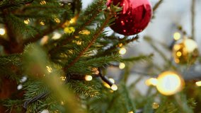 Detailed view of green pine branches decorated with reflective red and gold baubles and glowing fairy lights. Warm lighting and blurred background create cozy holiday atmosphere - Powered by Shutterstock - Get 15% off with code: PIKWIZARD15