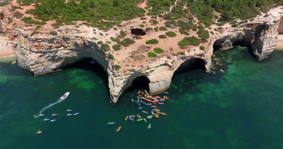 Aerial view of tour boats and kayaks approaching the Benagil Cave during summer in the Algarve coast, southern Portugal.