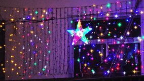 A vibrant outdoor holiday display featuring blue, purple, and multicolor LED string lights cascading down a building, centered around a glowing star decoration. - Powered by Shutterstock - Get 15% off with code: PIKWIZARD15