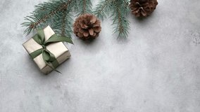A beautifully wrapped Christmas gift box with a green ribbon and pinecones, as a hand positions a blank card next to it, enhancing festive ambiance - Powered by Shutterstock - Get 15% off with code: PIKWIZARD15