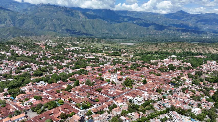 A wide circling the historic town center of Santa Fe de Antioquia, Colombia, focusing on the prominent Cathedral Basilica of the Immaculate Conception in the main square