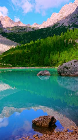 Turquoise Lake Sorapis surrounded by dramatic Dolomite peaks, crystal-clear water reflecting rugged mountains. Serene alpine landscape, breathtaking nature scene, travel. Vertical 