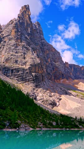 Turquoise Lake Sorapis surrounded by dramatic Dolomite peaks, crystal-clear water reflecting rugged mountains. Serene alpine landscape, breathtaking nature scene, travel. Vertical
