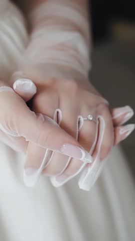 Vertical video. Close-up of the bride's hands in white transparent wedding gloves, slow motion. Wedding accessories. Wedding day.