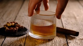 Whisky glass spinning beside cigar and chocolate treats. Premium whiskey, cigar and chocolate still life in motion. Elegant whiskey rotation featuring cigar and chocolate. Luxury whiskey spin. - Powered by Shutterstock - Get 15% off with code: PIKWIZARD15