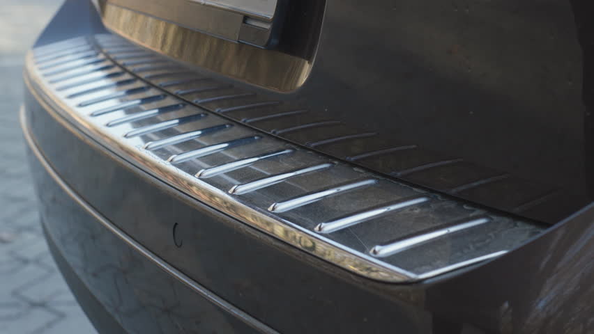 Car trunk door automatic opening with premium chrome bumper sill detail and clean original sound, close up rear view outdoors