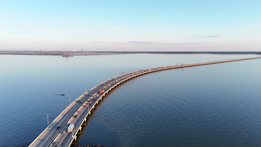 Aerial View Of Long Monitor Merrimac Memorial Bridge Tunnel crossing water of Hampton Roads Channel with a distant harbor and open sky Newport News Virginia, conveying travel, infrastructure.