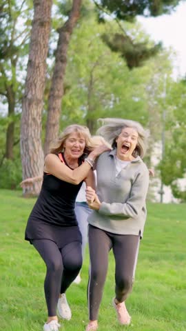 Senior women laughing and running together in a park