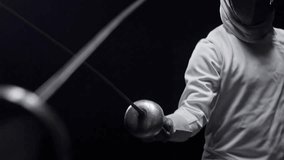 Two professional fencers fighting with foils in a dark studio in slow motion, highlighting fencing, sports action, and combat skills in HD. - Powered by Shutterstock - Get 15% off with code: PIKWIZARD15