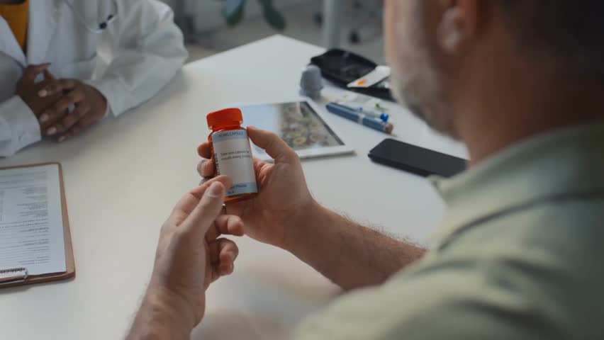 Medium close-up of hands of a mature man holding a container with pills, highlighting healthcare, medication, and medical treatment in HD.