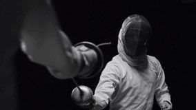 Two professional fencers in protective uniform train and spar with foils in a dark studio, capturing sport, precision, and motion in 4K. - Powered by Shutterstock - Get 15% off with code: PIKWIZARD15