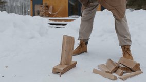 Cropped shot of an unrecognizable man chopping wood with an axe in a snowy front yard, showing winter preparation, strength, and seasonal outdoor work. - Powered by Shutterstock - Get 15% off with code: PIKWIZARD15
