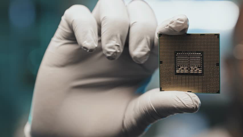 Selective focus on an engineer’s hand in sterile gloves holding a computer microprocessor, highlighting technology, electronics, and precision work in 4K.