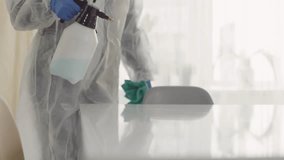 Slow-motion of a woman in a disposable full-body suit and gloves disinfecting a surface, showing hygiene, safety, and cleaning protocols in 4K. - Powered by Shutterstock - Get 15% off with code: PIKWIZARD15