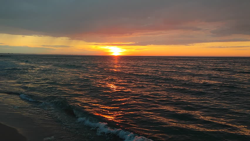 Sunrise or sunset at sea. The rising or setting sun over the horizon at sea. Dawn in the sky with dark rainy clouds. Sunset with large clouds before rain in sky. Nature backdrop. Natural background