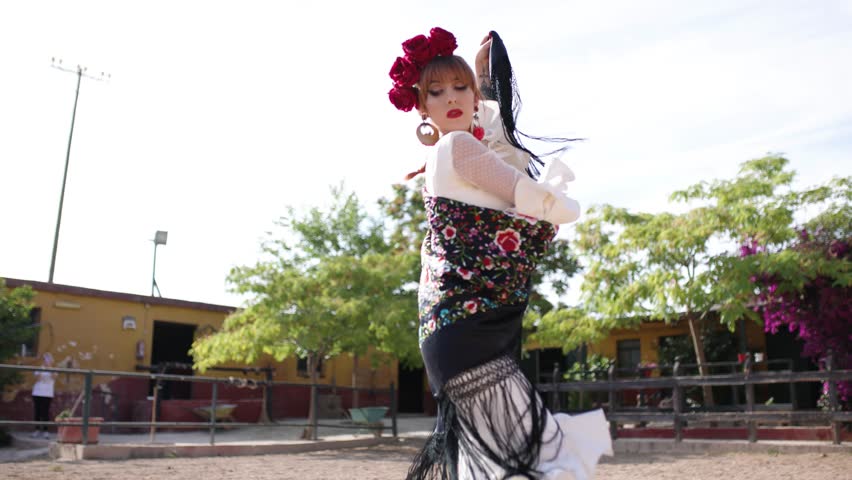 Passionate female dancer in a traditional white dress performing a beautiful and sensual flamenco dance with a black manila shawl outdoors