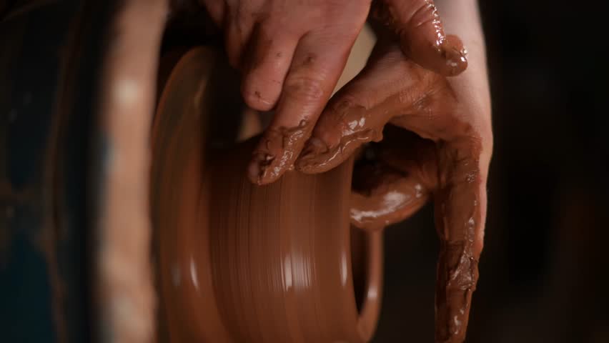 Potter shaping clay pot on pottery wheel close-up. Vertical video