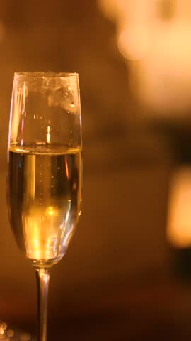 Closeup of two glasses one for champagne and one for wine with sparkling reflections warm evening light and cozy cinematic lamp atmosphere capturing half full drinks and romantic mood