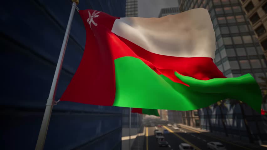 Oman national flag waving along a modern city street under clear daylight, surrounded by buildings, palm trees and light traffic within an urban environment. The distinctive textile features three horizontal bands of white, red, and green, with a vertical red stripe at the hoist charged with the national emblem. As the fabric undulates in the breeze from the Gulf, the Khanjar dagger and crossed swords become visible, symbolizing traditional weaponry and honor. The bright sun illuminates the vibrant colors: white representing peace and the Imam, red standing for historical battles, and green signifying the fertility of the Jebel Akhdar mountains. In the background, low-rise white-washed architecture typical of Muscat creates a pristine aesthetic, contrasting with the azure sky. Date palms line the median, swaying gently alongside the banner. Vehicles move rhythmically along the asphalt, reflecting the Sultanate's bustling economy and modern infrastructure. This footage perfectly captures the patriotic spirit seen during National Day celebrations in November, highlighting the blend of ancient heritage and contemporary development. The ensign snaps crisply, casting fleeting shadows on the pole, while the surrounding district buzzes with daily activity. Travelers and locals alike pass by this symbol of unity, which stands as a proud marker of identity in the Arabian Peninsula. The scene evokes a sense of stability and progress, suitable for documentaries regarding Middle Eastern politics, tourism campaigns for the diverse landscapes of the region, or news segments covering diplomatic events in the capital.