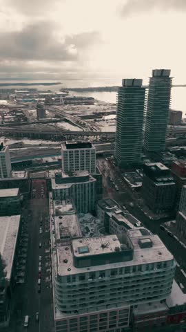 Cinematic aerial view of Toronto’s historic Distillery District featuring the Gardiner Expressway, CN Tower and TTC streetcar at the Distillery Loop. 
