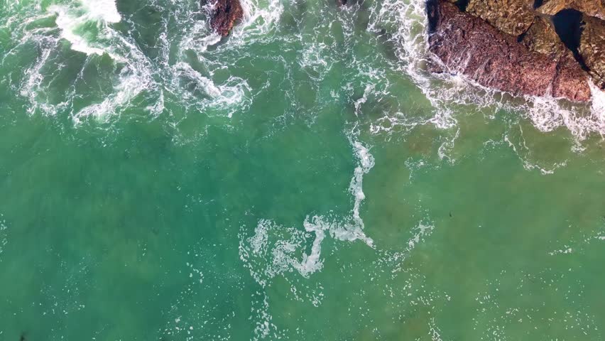 Turquoise waters meet the shore, framed by dramatic coastal cliffs and crashing waves along the rugged and beautiful California coastline