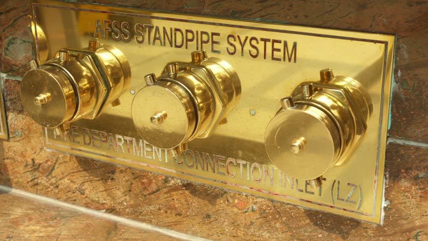 Integrated safety panel in stone, closeup of brass safety integrated into stonework, aesthetic brass safety cover seamlessly incorporated into stone with functional valves and identification markers