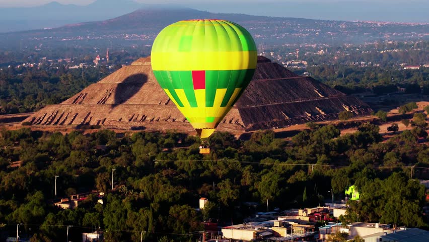 Aerial view of a hot air balloon circling Teotihuacan pyramids, Mexico at golden hour, capturing iconic ancient structures, warm sunlight, and scenic aerial perspectives.