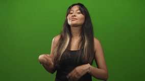 Young latina woman, brunette, smiling while presenting open palms toward camera in studio setting; playful confidence. - Powered by Shutterstock - Get 15% off with code: PIKWIZARD15