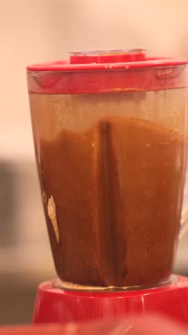 Iced coffee blended with crushed ice in large blender at street cafe setting