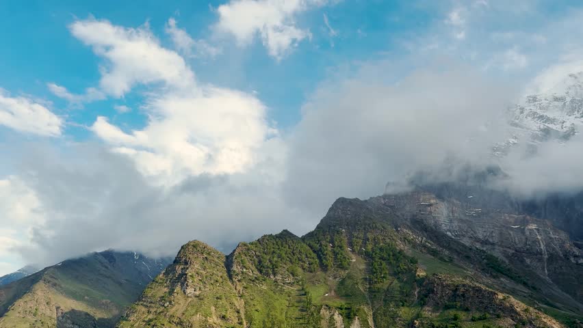 4K Landscape shot of clouds under the snowy Himalayan mountain peak after winter storm during evening as seen from Khangsar village in Lahaul and Spiti district, Himachal Pradesh, India. Nature view.