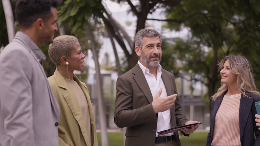Group of diverse business people having a conversation in a park. Mature male manager explaining the strategy to his team outdoors
