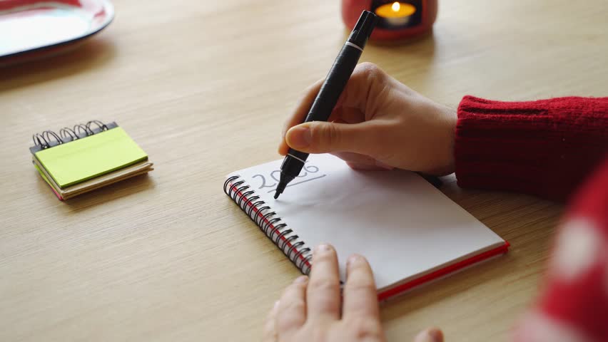 New year's resolutions. Hand starting 2026 goals indexed list in notebook