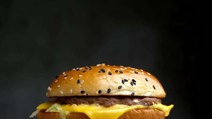 Close up burger with US flag, scene emphasizes classic American burger made from domestic beef, cheese and bread from national farms.