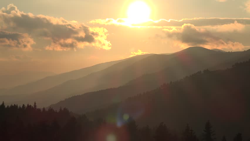 Time lapse sunset over successive forest covered ridges of the Ural Mountains. Golden light fades across Russian highlands as layered Urals silhouettes deepen toward evening.