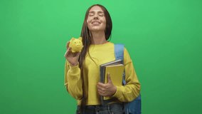 Young student woman holding yellow piggy bank and clutching notebooks, eyes closed and smiling in studio; future savings confidence. - Powered by Shutterstock - Get 15% off with code: PIKWIZARD15