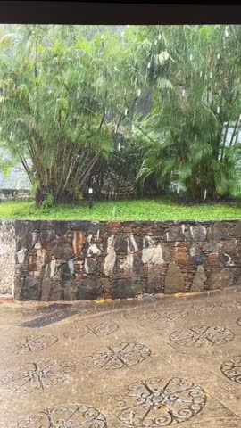 Outdoor View of heavy Rain on Textured Stone Wall and Tiled Ground